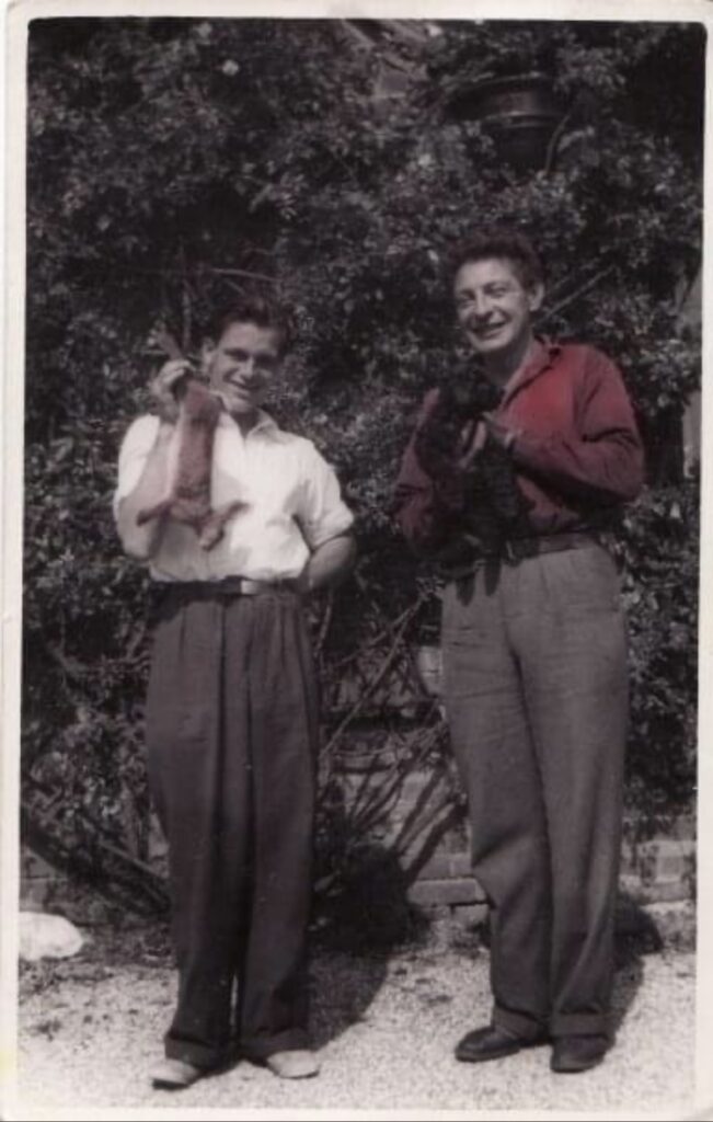 two men holding rabbit and dog 